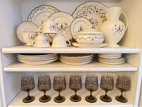 Full lot displayed on shelving showing dinnerware stacks, tureen, pitcher and goblets