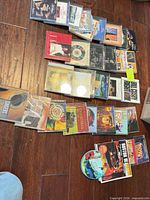 Curved lineup of assorted CD jewel cases on floor showing various titles