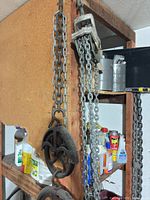 Cast iron pulley blocks with chain hanging on shelving