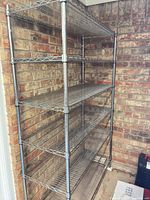 Full view of assembled six-shelf chrome wire shelving unit against brick wall