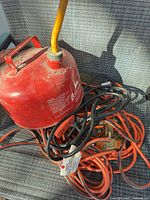 Gas can and coiled extension cords on chair