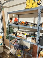 Overall view of metal shelving with power tools, cords, artificial tree and hardware
