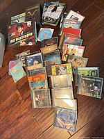 Overview of entire lot showing multiple stacks of CDs and two DVD box sets