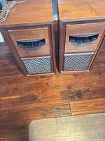 Full view of both speakers showing wood cabinets, horn tweeters, metal grilles