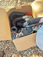 Box containing coiled flexible duct hoses and several boxed couplers