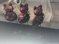 Front view of three copper-bronze tone metal frog musician figurines