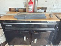 Front view of black Yukon rolling tool chest showing wood top, drawer, cabinet doors and casters