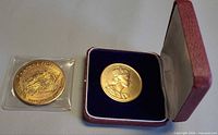Overview of both coins; coronation medallion in open case, Hawaii dollar in sleeve