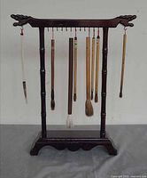 Front view of wooden stand with eight brushes hanging