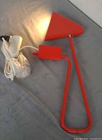 Full lamp coiled with plug showing red metal arm, triangular head