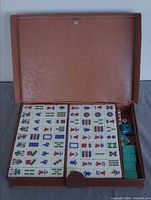Open vinyl case showing arranged Mahjong tiles and side compartment with accessories