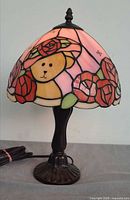 Full view of lamp lit showing stained glass shade, metal base, and power cord