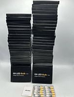 Two tall stacks of sealed black DiCUNO G9 LED Bulb 10-pack boxes with one blister tray of bulbs displayed