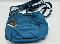 Full view of Kedzie blue bucket bag with straps and front zip pocket