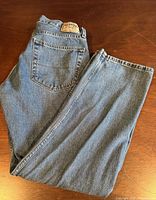 Folded pair of blue denim jeans showing back pocket and overall color