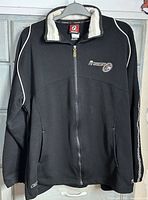 Front view of black Reebok Allen Iverson zip jacket on hanger showing overall design