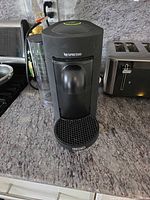 Front view of black Nespresso Vertuo ENV150 with water tank and drip tray