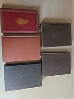 Five cloth hardcover books stacked face up showing cover colours