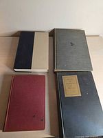 Four cloth-bound books laid out showing covers