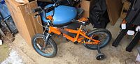 Full view of orange Mongoose 16-inch kids bike with training wheels
