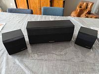 Front view of two SB-S50 satellites and SB-C80 center speaker on table