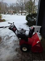 Left side profile of Toro 824 snow blower showing red body, chute and tires