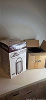Zojirushi AY-AE25N boxed unit beside open carton with base