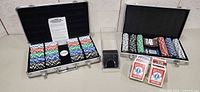 Both open aluminum cases, chip trays, playing cards displayed