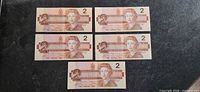 Front view of five 1986 Canadian $2 banknotes spread out
