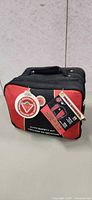 Front of red and black roadside safety kit bag with tag