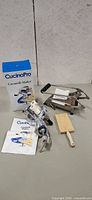 Full lot view showing cavatelli maker, potato cutter, gnocchi board, box and manuals