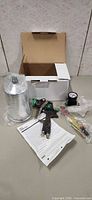 Full set showing spray gun, cup, regulator, tools, manual and box