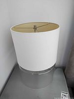 Full view of one lamp showing white drum shade and clear glass base