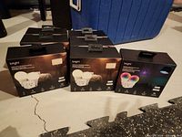 Six Bright Smart Wi-Fi LED Bulb & Plug Kit boxes and one Bright colour-changing bulb box grouped