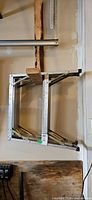 folded aluminum step ladder hanging on wall, front view