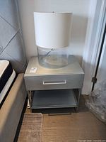 Full view of nightstand beside bed showing drawer, handle and shelf