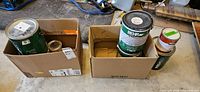 Two boxes containing multiple paint cans