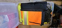 Folded safety clothing in clear storage bin