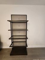 Full view of tall shelving unit showing all shelves, wood frame, upholstered back