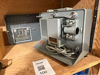 Argus M-500 projector in open carrying case with power cord visible