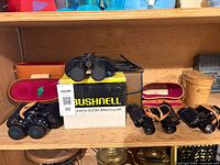 All binoculars, cases and Bushnell box displayed on shelf