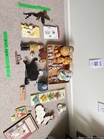 Entire assortment laid out on carpet showing nesting dolls, music box, carved figures, plaques, tin and other items