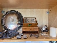 Overview showing round tray, presentation box with spoons, small bowl, square dishes, knife rests, candle