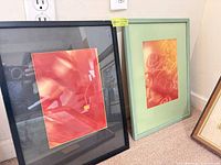 Abstract print in black frame beside abstract print in green frame