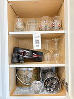 Cabinet shelves showing tumblers, wine glasses, Vinturi aerator box, stone birds, ice bucket, bar tool holder