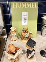Four figurines and Hummel book on countertop