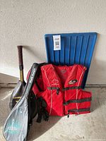 Group shot of life jacket, two tennis rackets with covers, blue sled