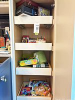Full cabinet view showing multiple pull-out drawers with board games, art supplies and magnetic toy bag