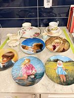 Lot overview showing decorative plates, teacups, creamer, sugar and serving plate