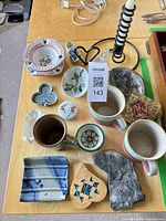 All items laid out showing mugs, dishes, wooden box, fossil slab